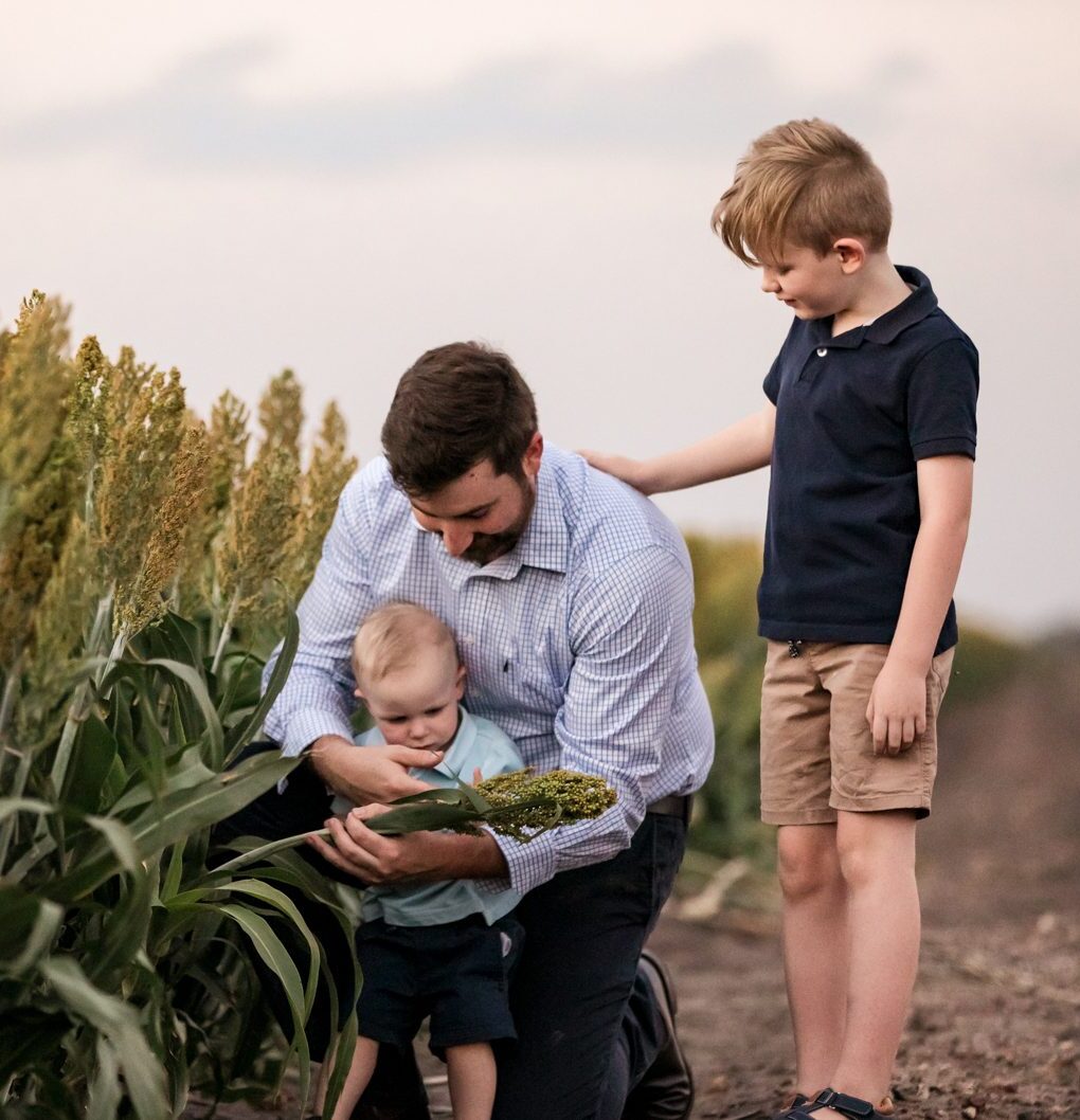 A Carrick Aland client with his sons in a sorghum field at dusk